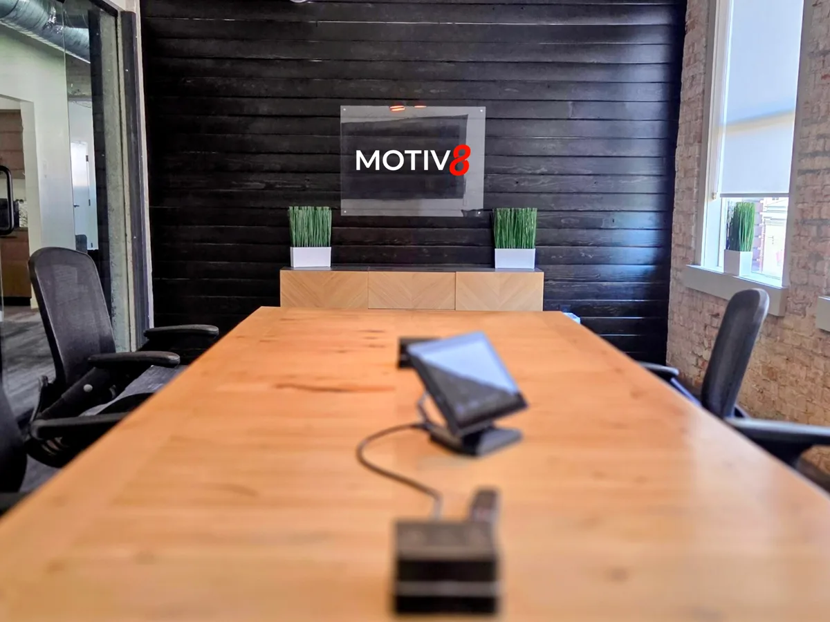 Motiv8 conference room with the Motiv8 logo on a dark wood wall at the Ogden, Utah office